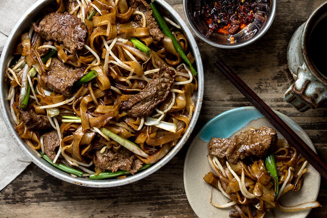large plate of beef chow fun on a wooden table.