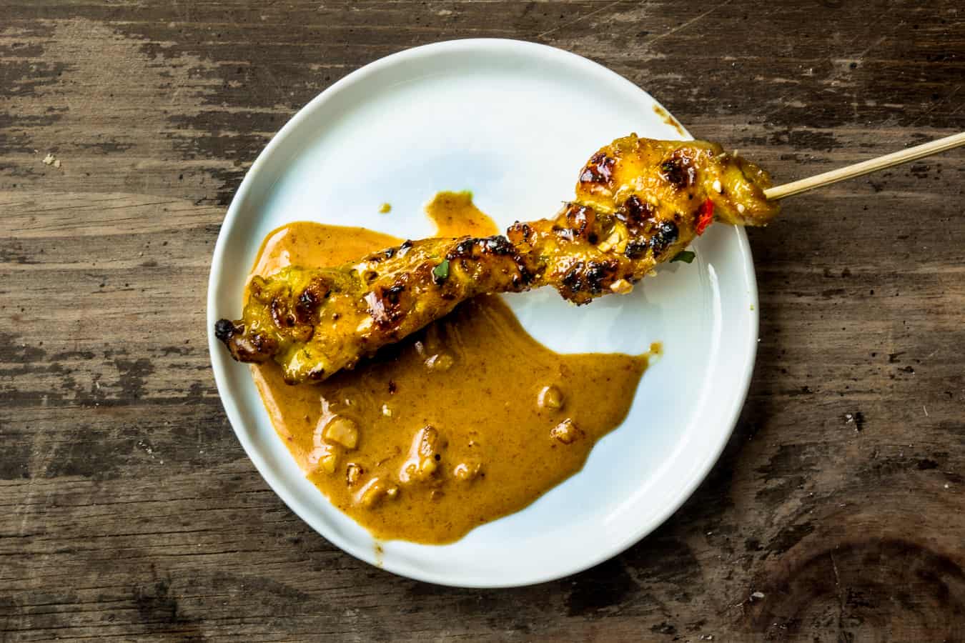 Chicken satay with peanut sauce on a white plate