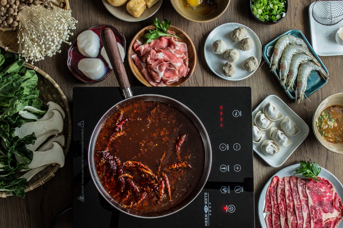 Hotpot with a chili oil broth, with Asian seafood such as scallops, shrimp around the pot.