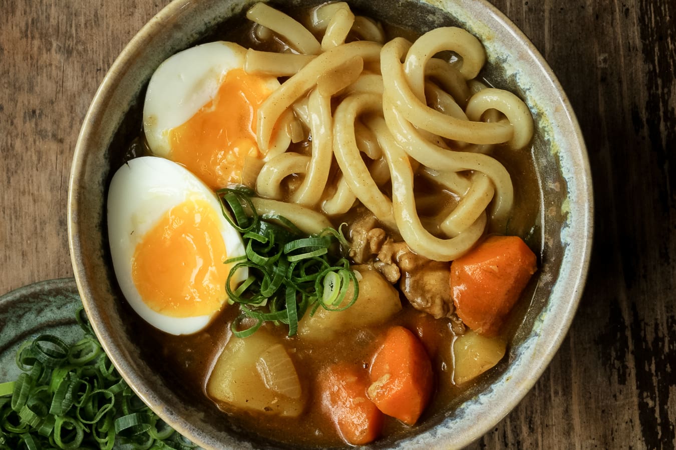 japanese curry soup with udon noodles and a soft bowl egg in a light bowl.