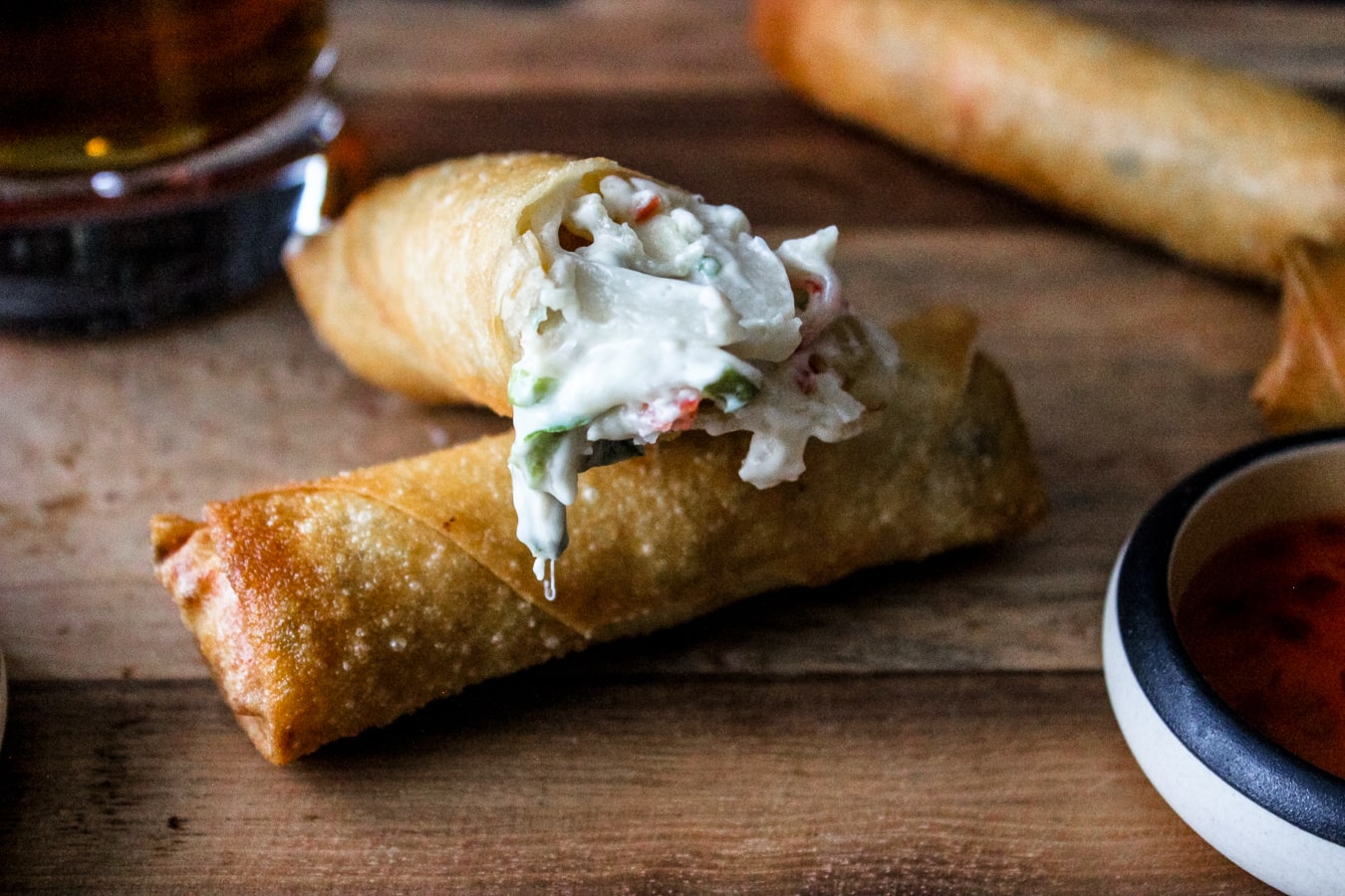 A closeup of a crab and cheese spring roll on a wooden cutting board