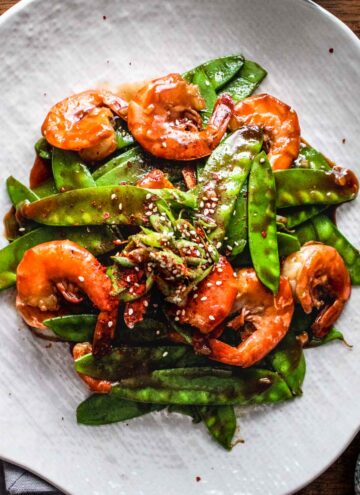 Asian shrimp with snow peas on a white plate.