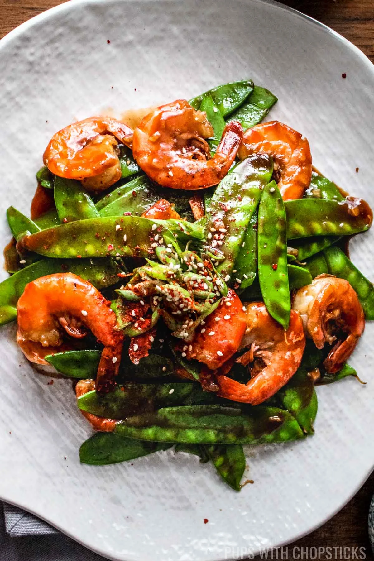 Asian shrimp with snow peas on a white plate.
