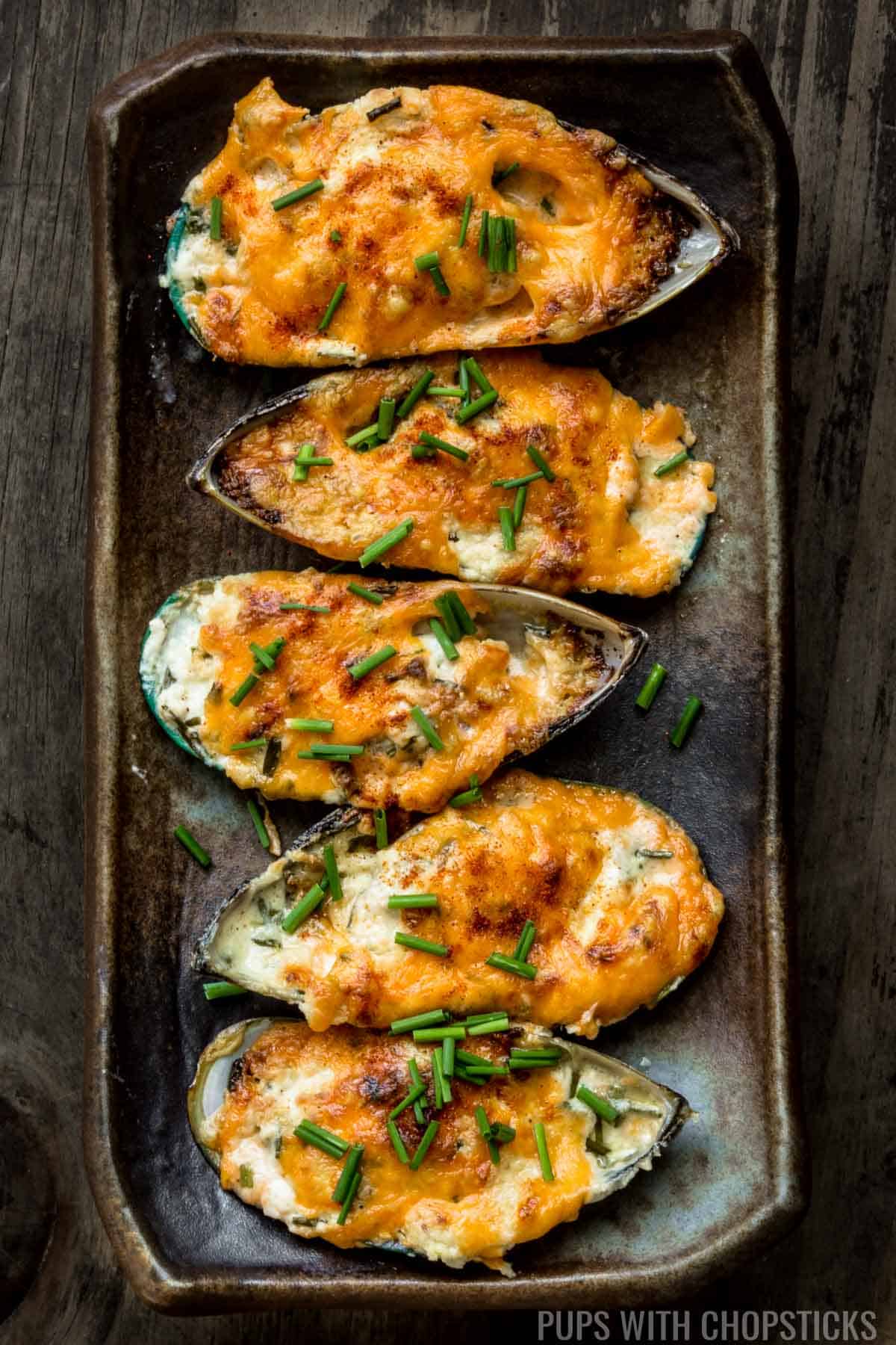 Garlic Cheese Baked Mussels on a plate with some chives on top