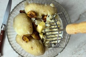 Mashing the garlic mashed potatoes with butter and roasted potatoes