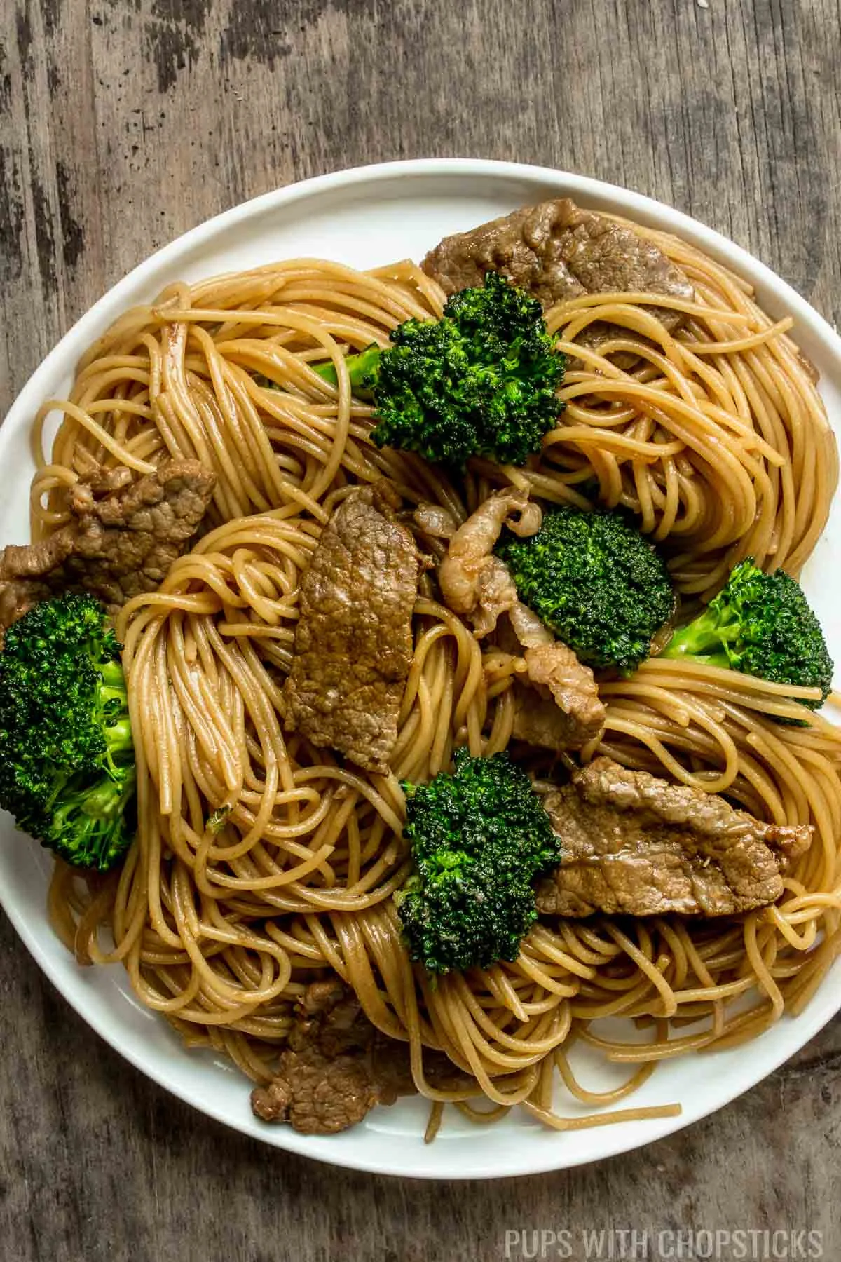 Closeup of beef and broccoli noodles stir fry on a white plate