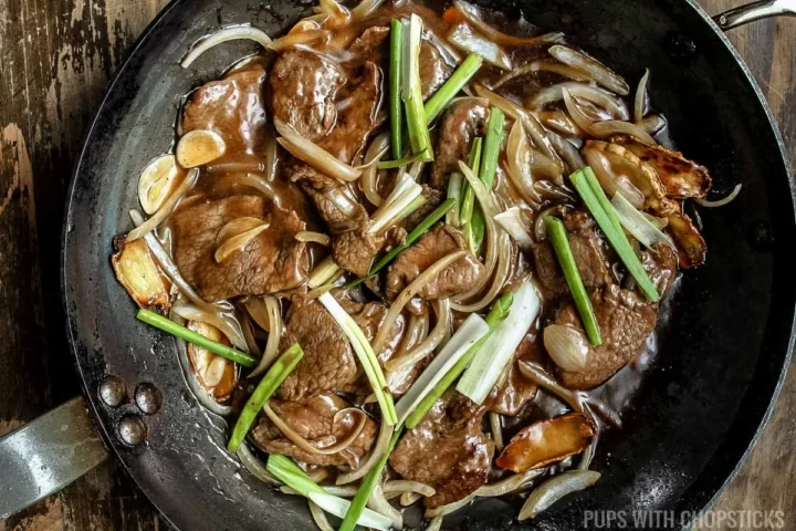 Beef and onion stir fry finished cooking in a frying pan.