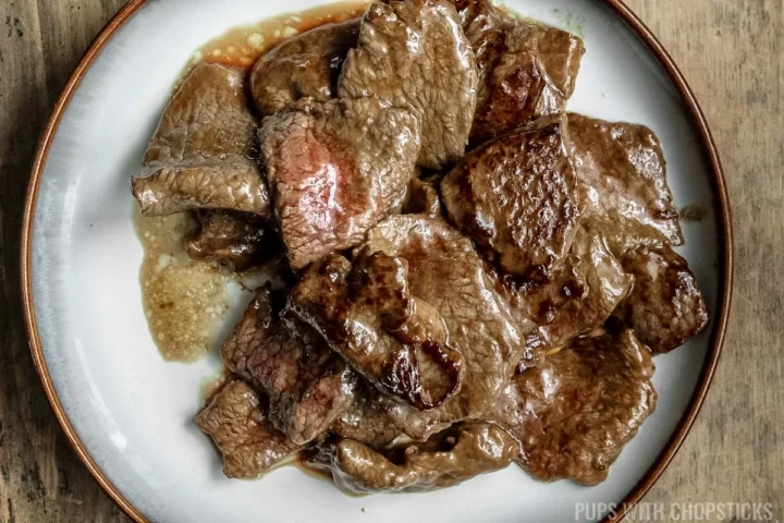 A plate of seared beef that has been partially stir-fried.