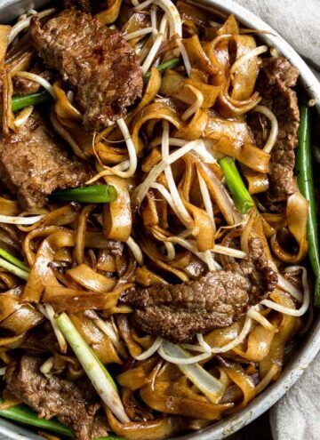 A close up for Chinese beef chow fun noodles in a metal bowl