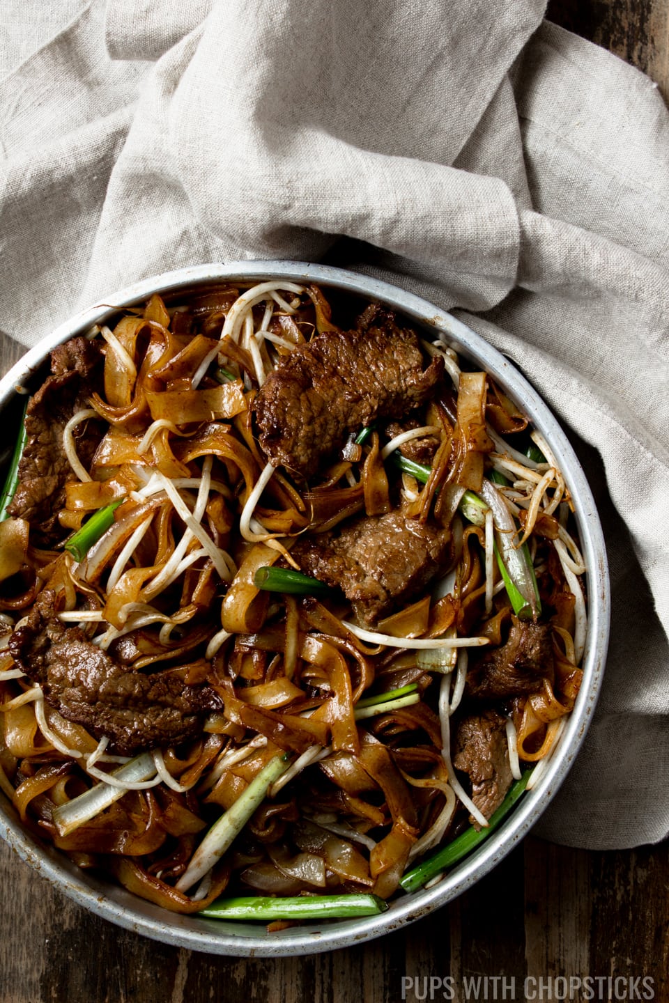 Beef Chow Fun (Beef Ho Fun) in a metal bowl with a handkerchief on the side