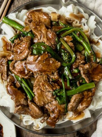 A plate of saucy beef chow ho fun with gravy served on a metal plate