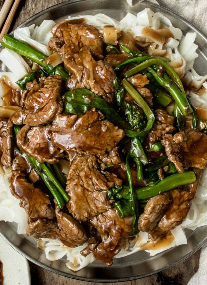 A plate of saucy beef chow ho fun with gravy served on a metal plate