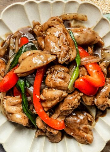 chinese black pepper chicken on a beige plate.