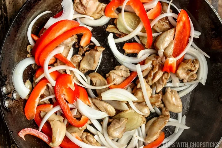 stir frying onions and red peppers with chicken.