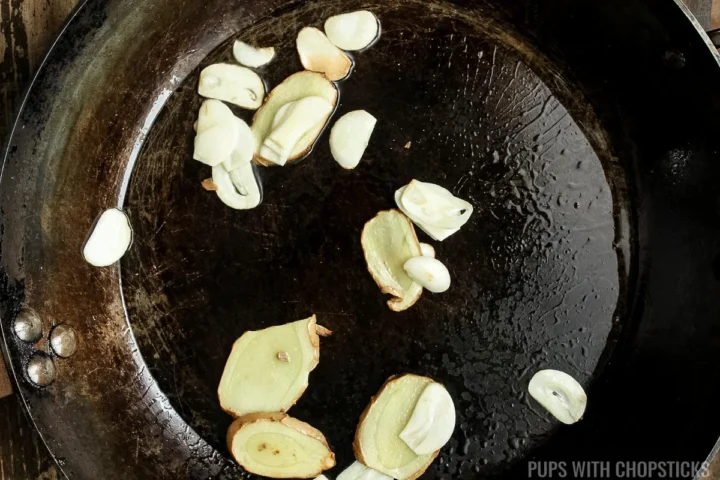 ginger and garlic slices being sautéed in a frying pan.