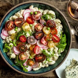 Roasted Garlic Miso Blue Cheese Pasta Salad in a large serving plate with plates and serving utensils