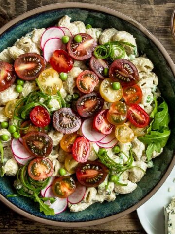 Roasted Garlic Miso Blue Cheese Pasta Salad in a large serving plate with plates and serving utensils