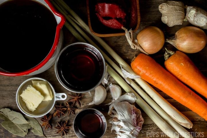 Ingredients laid out for bo kho (carrots, garlic, lemongrass, beef stock, butter, bay leaves, fish sauce, tomato paste, ginger, onion, star anise