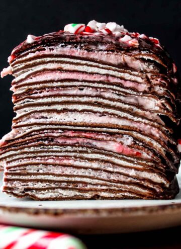 Closeup of Christmas candy cane chocolate mille crepe cake on a white plate.