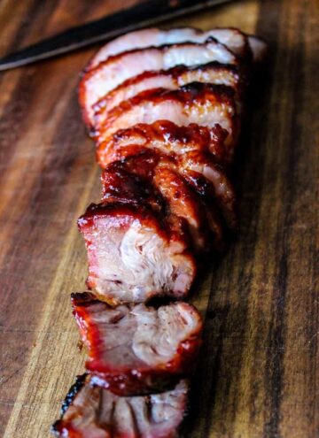 Char Siu (Chinese BBQ Pork) thinly sliced and fanned out on a cutting board.