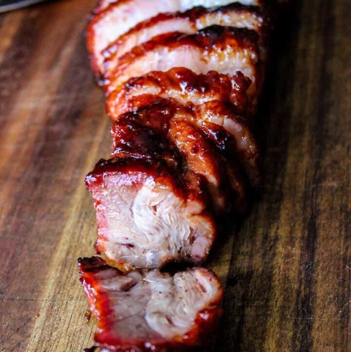 Char Siu (Chinese BBQ Pork) thinly sliced and fanned out on a cutting board.