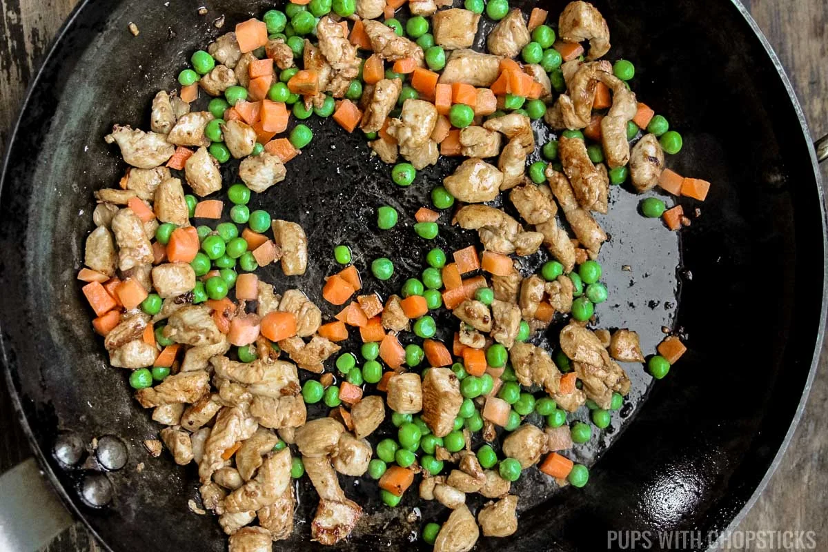 Add frozen peas and vegetables to frying pan.