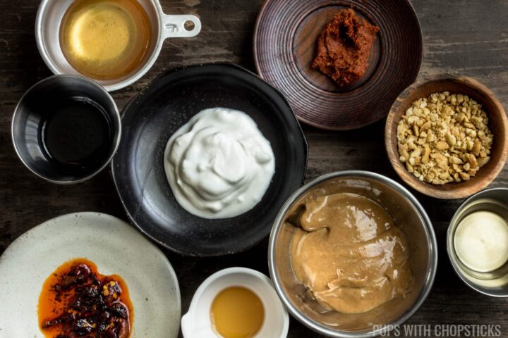 Ingredients laid out for peanut sauce (peanut butter, red curry paste, coconut cream, honey, fish sauce, sesame oil)