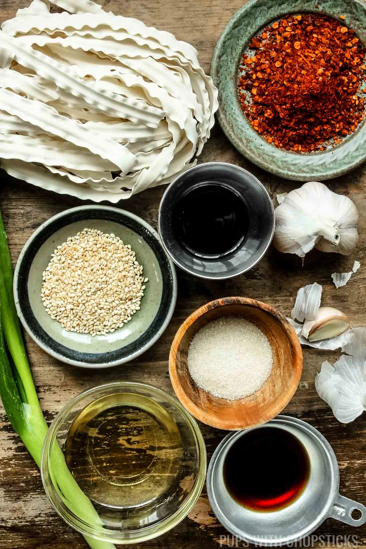 Ingredients for chili oil noodles (knife cut noodles, sichuan pepper flakes, soy sauce, vinegar, sugar, sesame oil, oil, garlic, green onions)