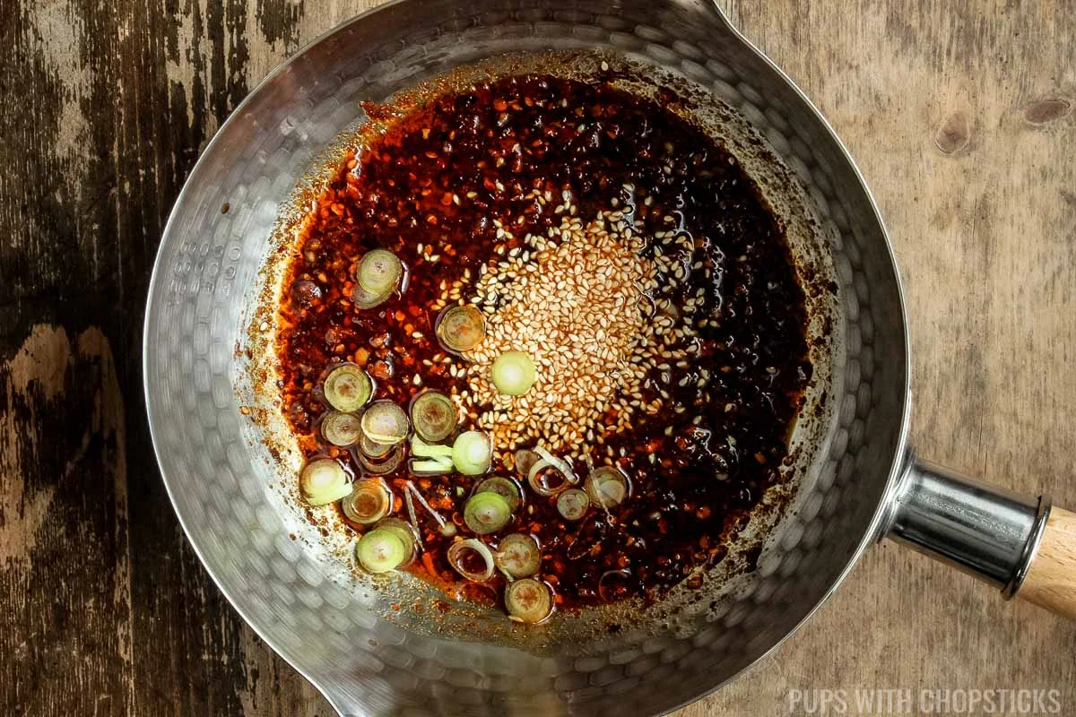 Adding the delicate aromatics like green onions, sesame seeds and toasted sesame oil into the chili oil