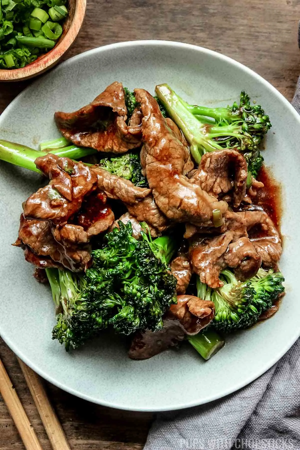 chinese beef and broccoli on a grey plate with wooden chopsticks.