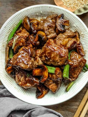 Chinese beef and mushroom stir fry on a white plate.