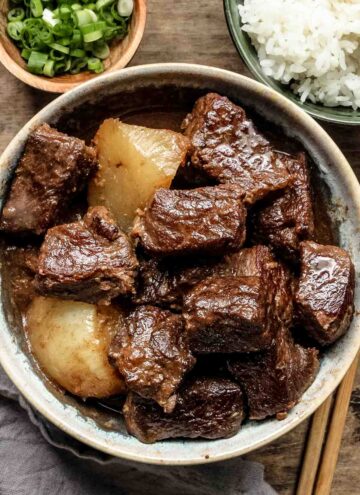Chinese braised beef stew in a white bowl on a wooden table.