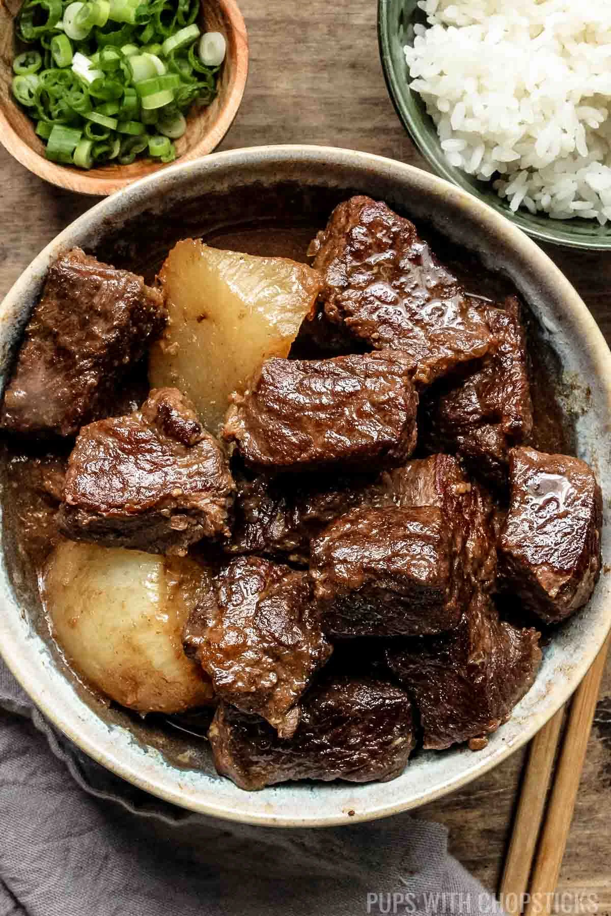 Chinese braised beef stew in a whilte bowl on a wooden table.