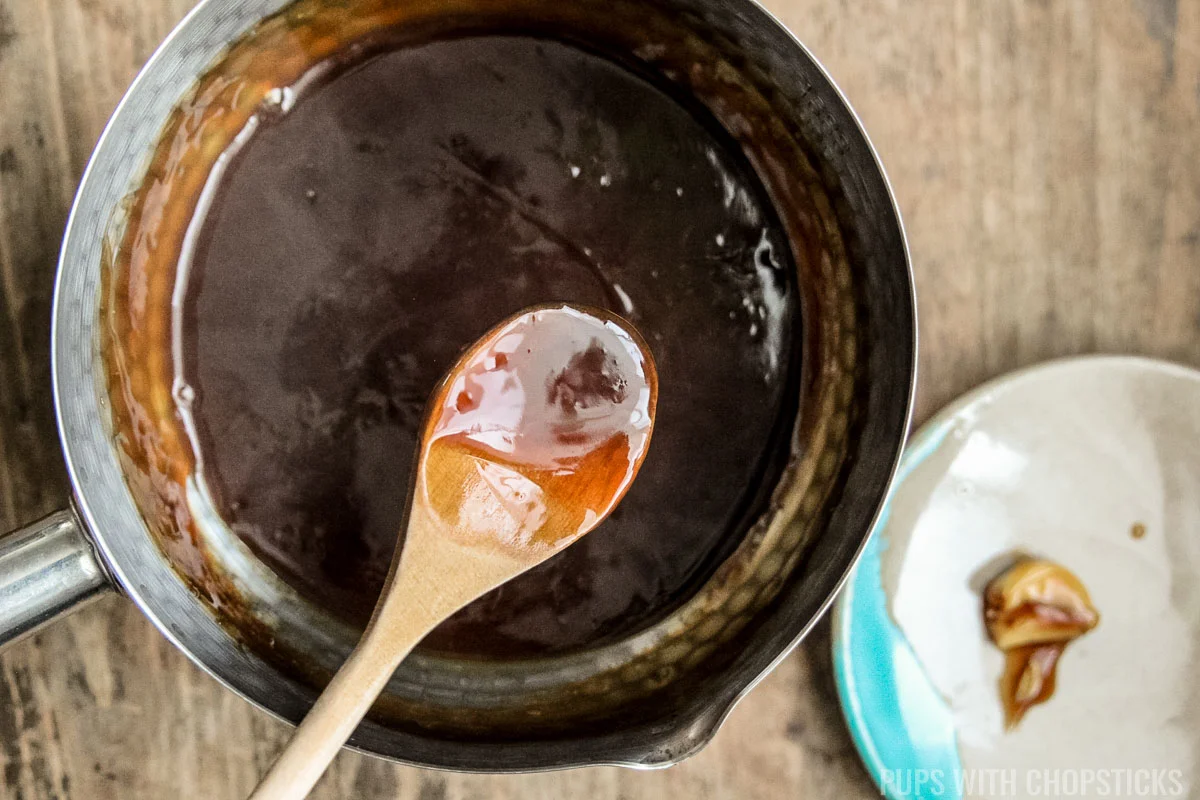Thickened Chinese brown sauce in a pot with a wooden spoon.