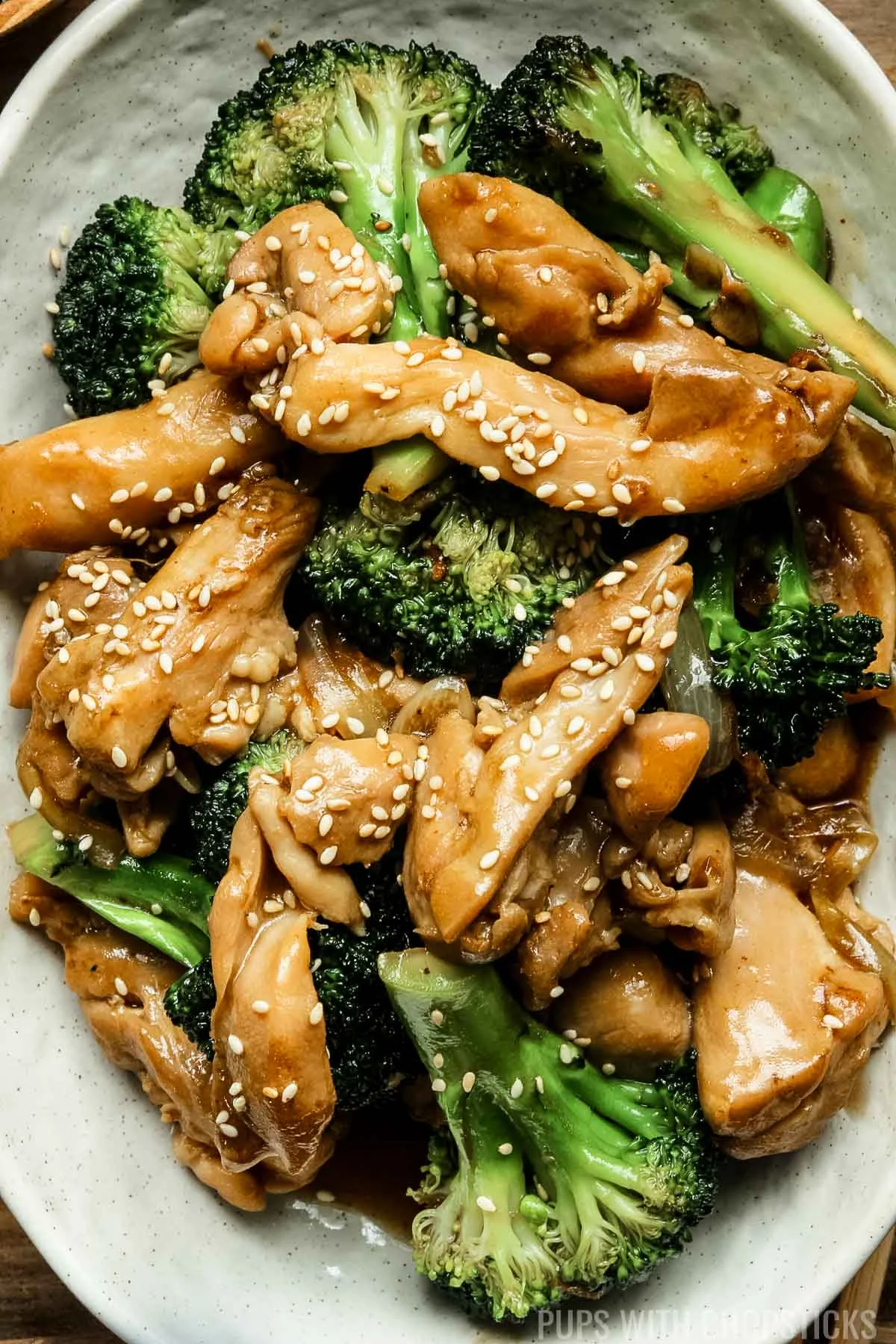 chicken and broccoli stir fry on a white plate on a wooden table.