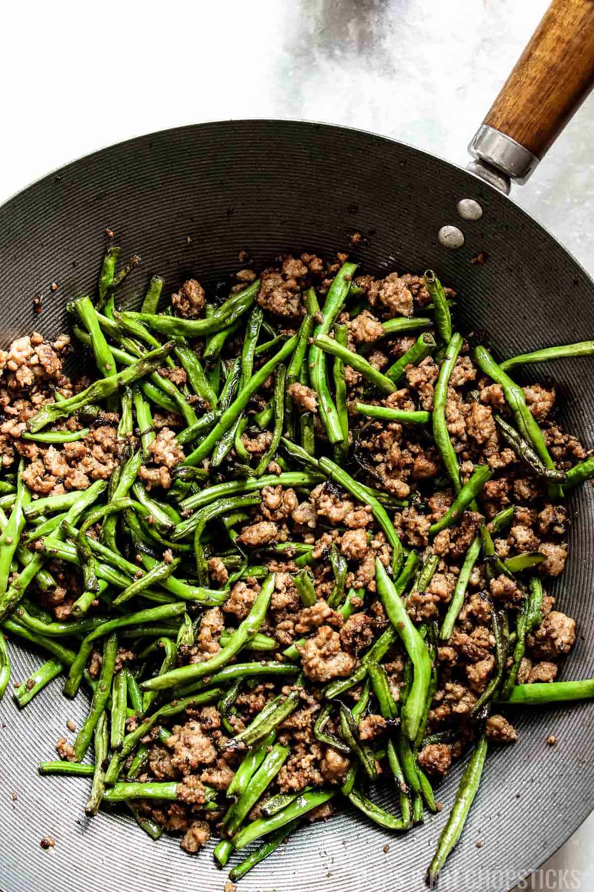 Chinese dry-fried long beans with minced pork and Chinese olive vegetable in a wok