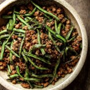 Close up of Chinese dry-fried long beans with minced pork in a beige bowl