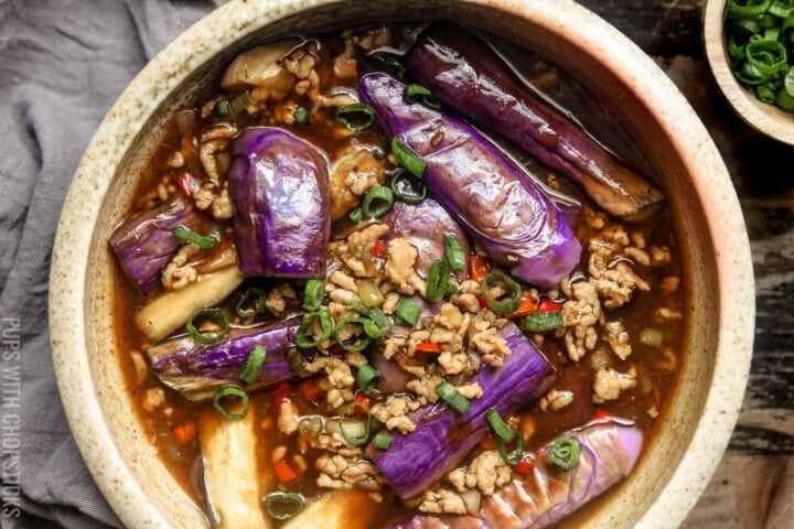 Overhead closeup picture of Chinese eggplant with garlic sauce in a large bowl served with green onions on the side