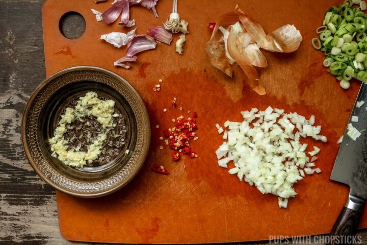 Garlic grated, onions and green onions finely chopped in preparation of making chinese eggplant