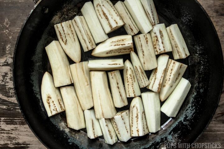 Cooking Chinese eggplant skin side down in a large frying pan