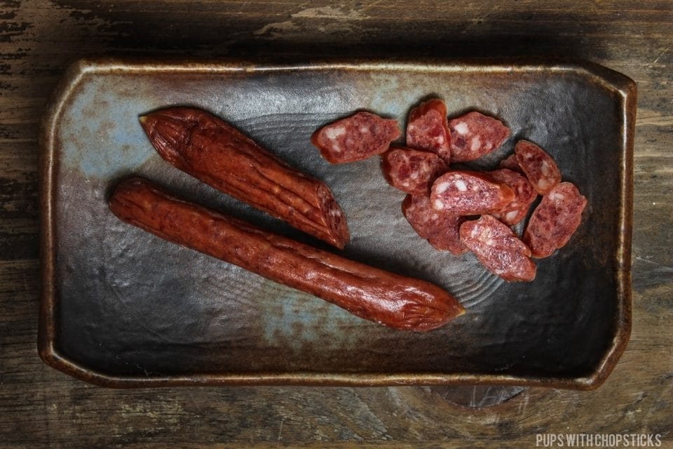 Chinese sausage cut up and placed on a brown plate.