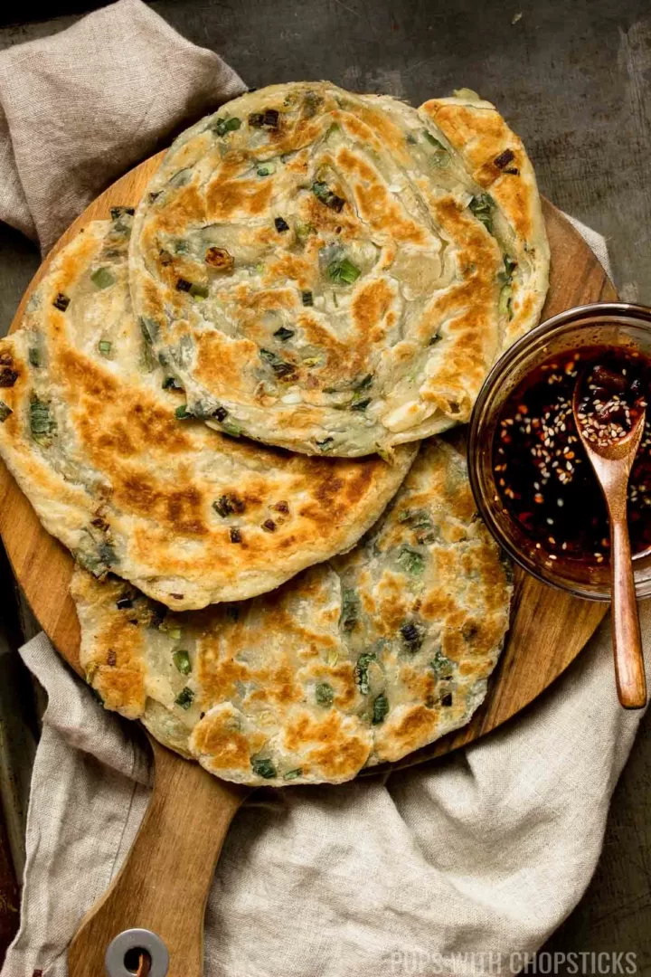 Chinese scallion pancakes on wooden board with dipping sauce