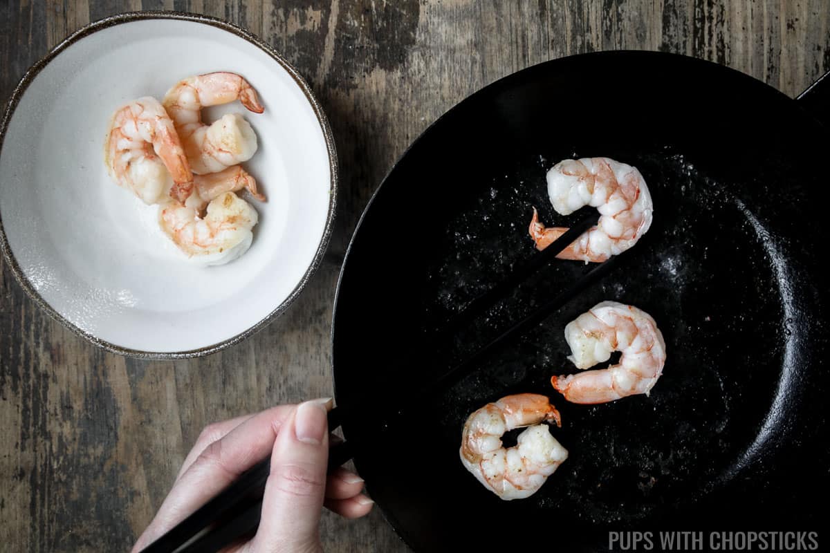 Cooked shrimp being removed from frying pan