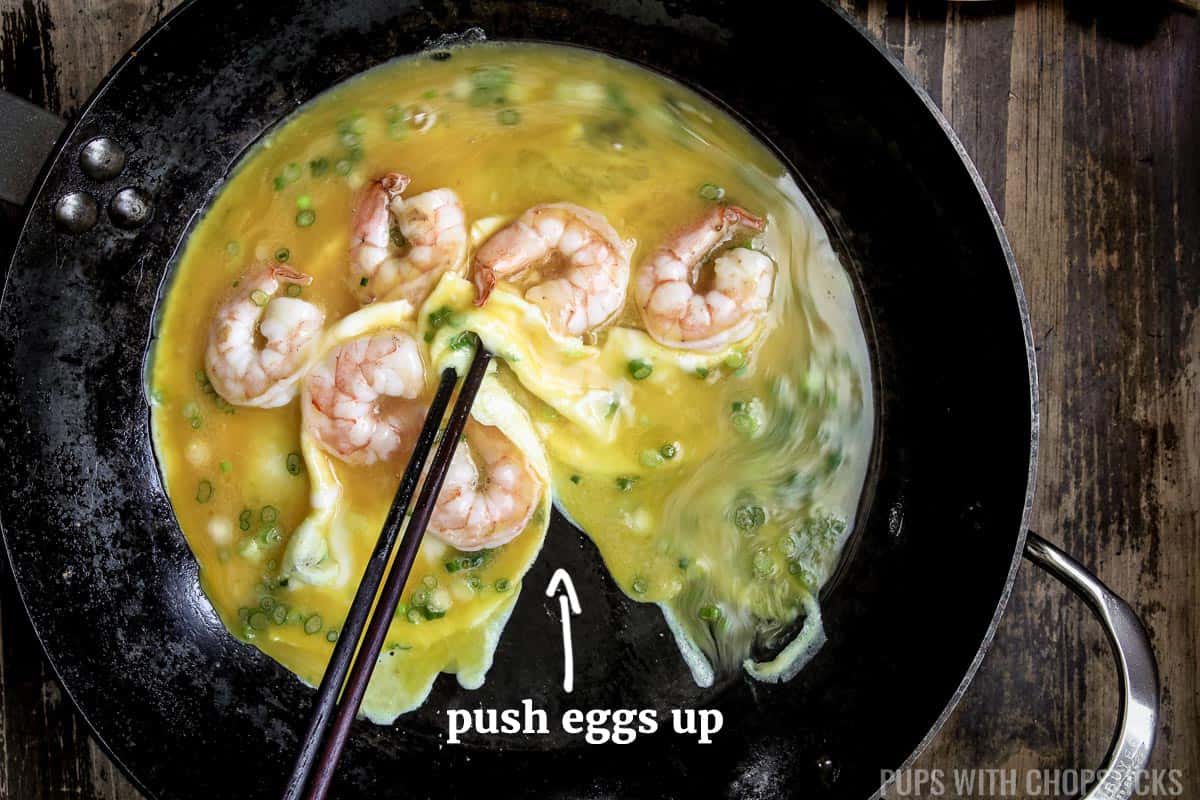 Pushing scrambled egg up with chopsticks in frying pan