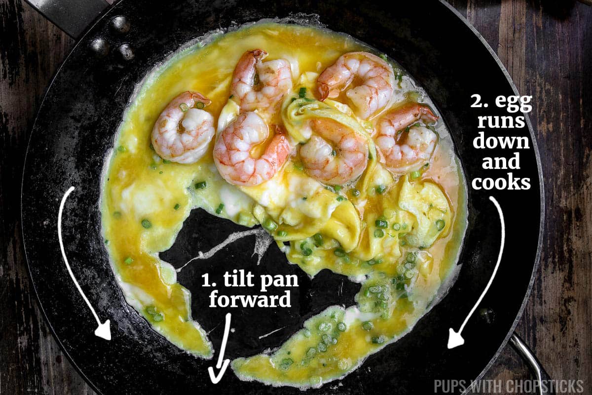 Tilting pan forward, so raw egg runs down to hot pan to cook.