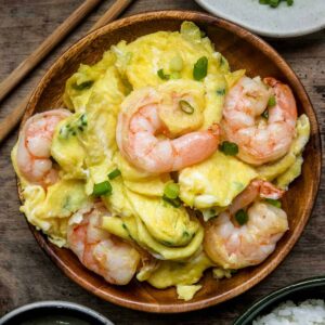 Chinese Scrambled Eggs with Shrimp served on a wooden plate with chopsticks