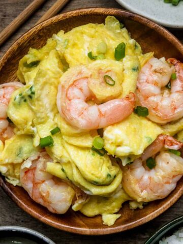Chinese Scrambled Eggs with Shrimp served on a wooden plate with chopsticks