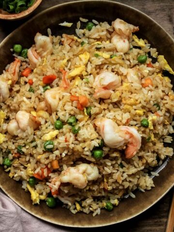 chinese shrimp fried rice on a brown plate with pink towel.