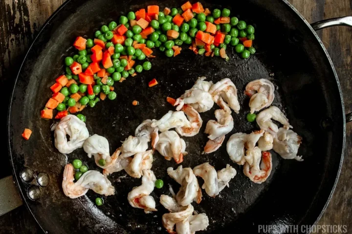 adding shrimp into frying pan and cooking it.