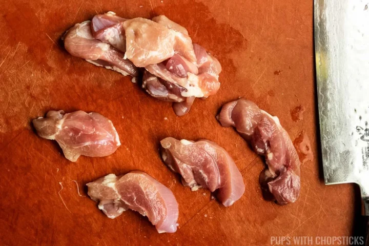 a cutting board with chicken pieces cut into 1.5 inch pieces.